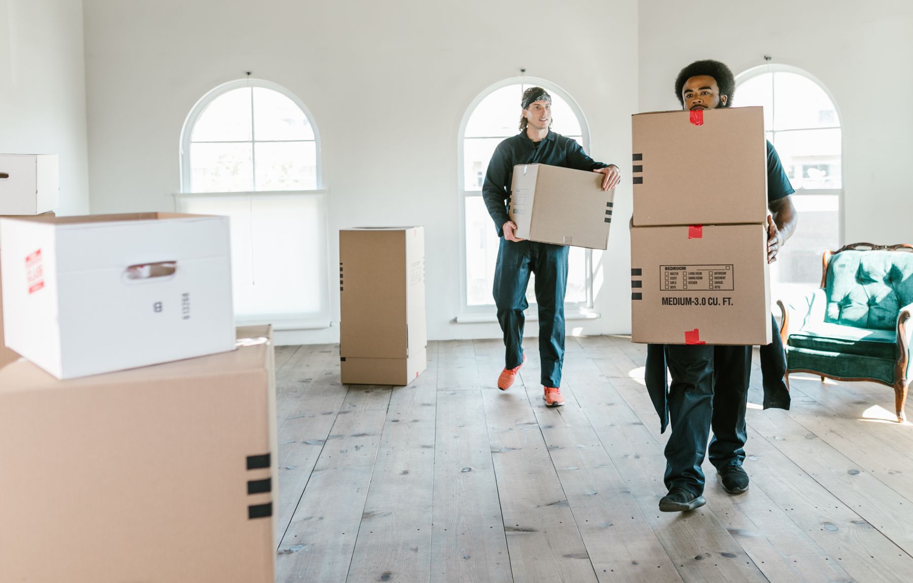 Movers carrying boxes into a bright home