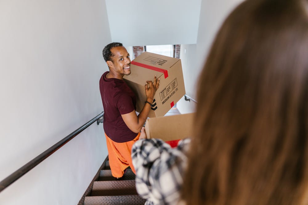 Mover carrying a box up the stairs